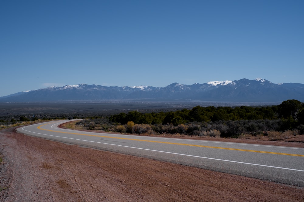 gray concrete road near green trees under blue sky during daytime