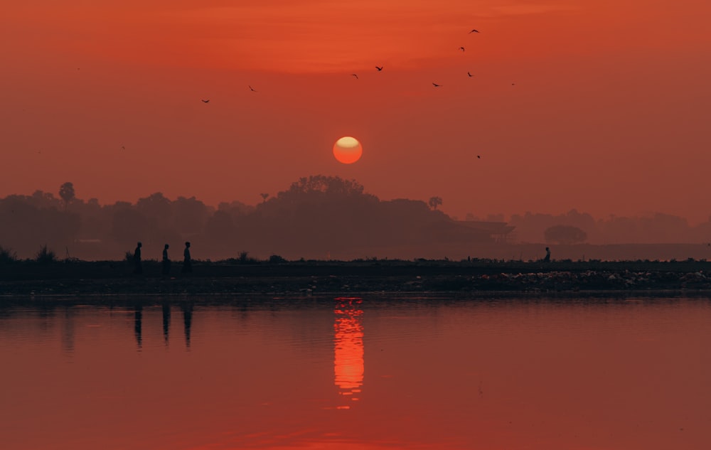 Silueta de edificios de la ciudad cerca del cuerpo de agua durante la puesta del sol