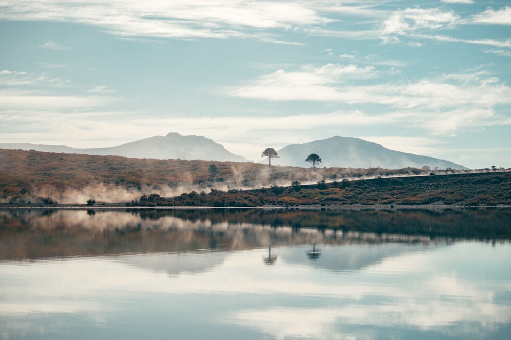 lake near mountain under blue sky during daytime