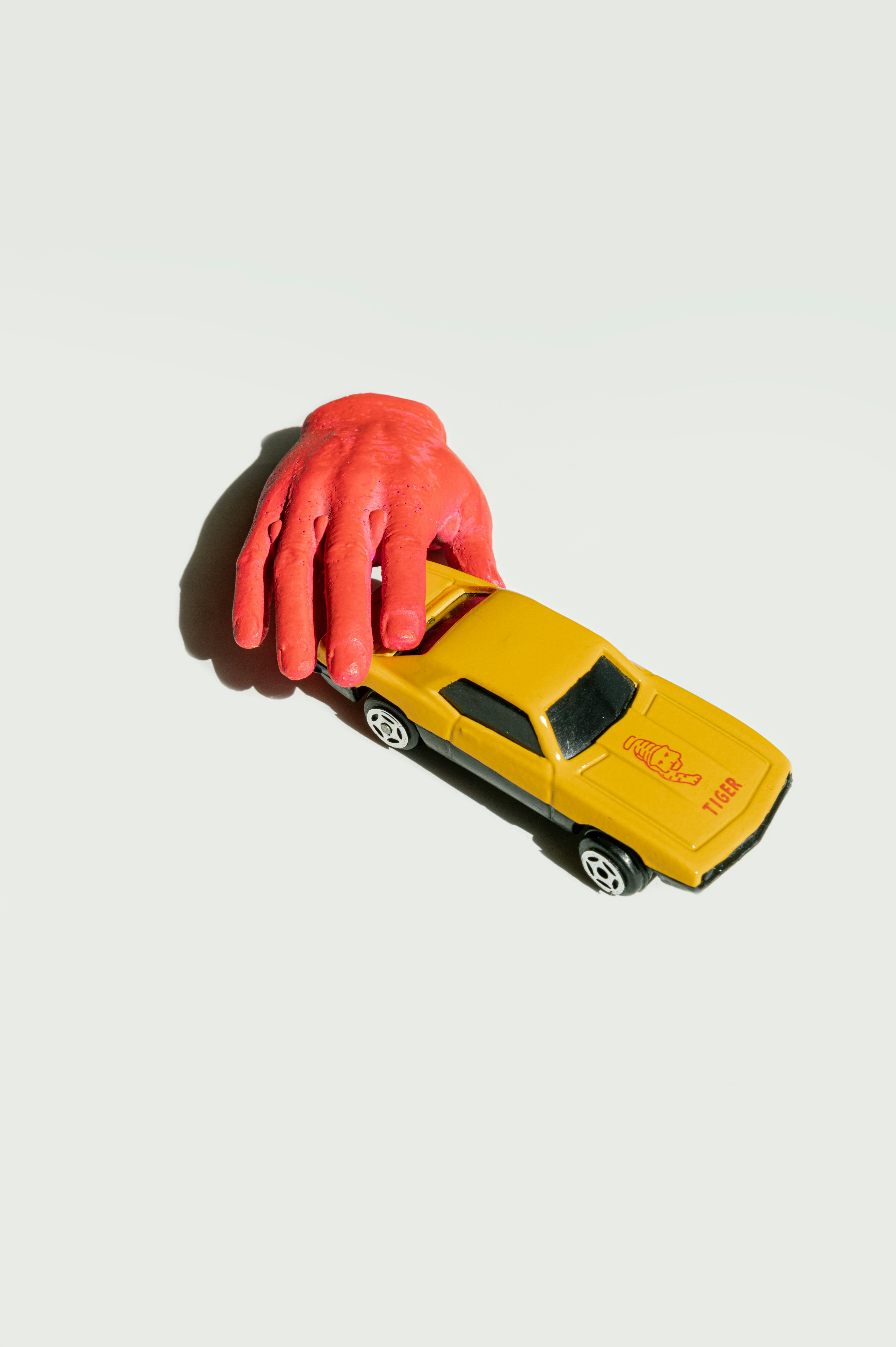 Die-cast car on white background and pink neon hand