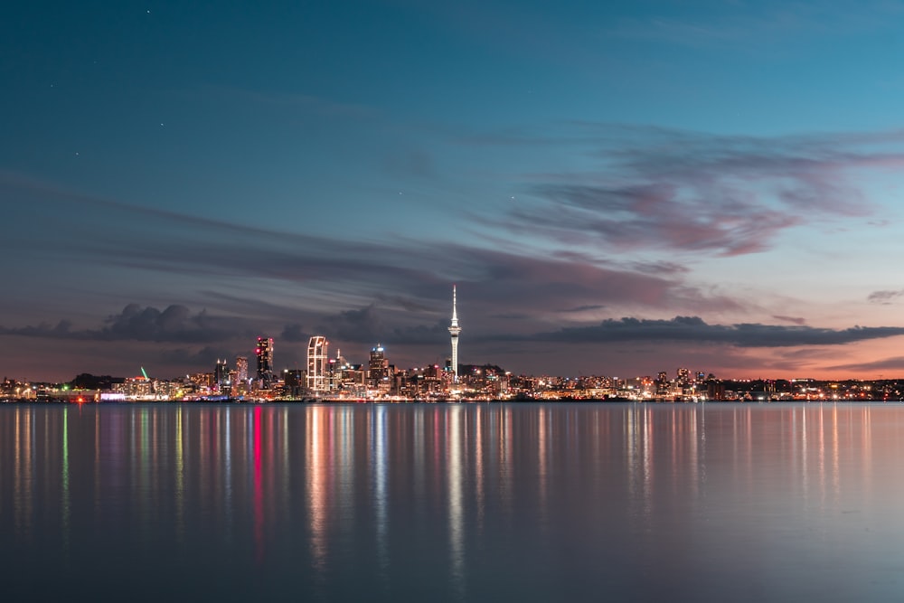 city skyline across body of water during night time