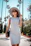 A stylish woman carrying a compact Couture Vivi shoulder bag on a sunny city street.