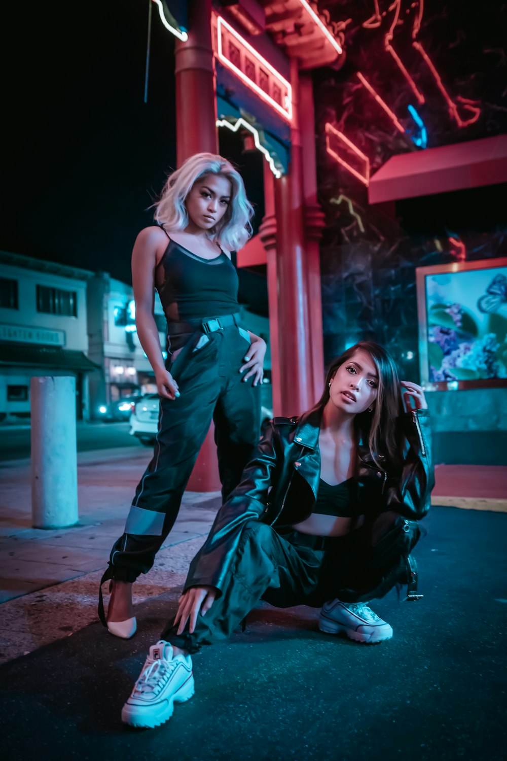 woman in blue tank top and black leather jacket standing beside woman in black leather jacket