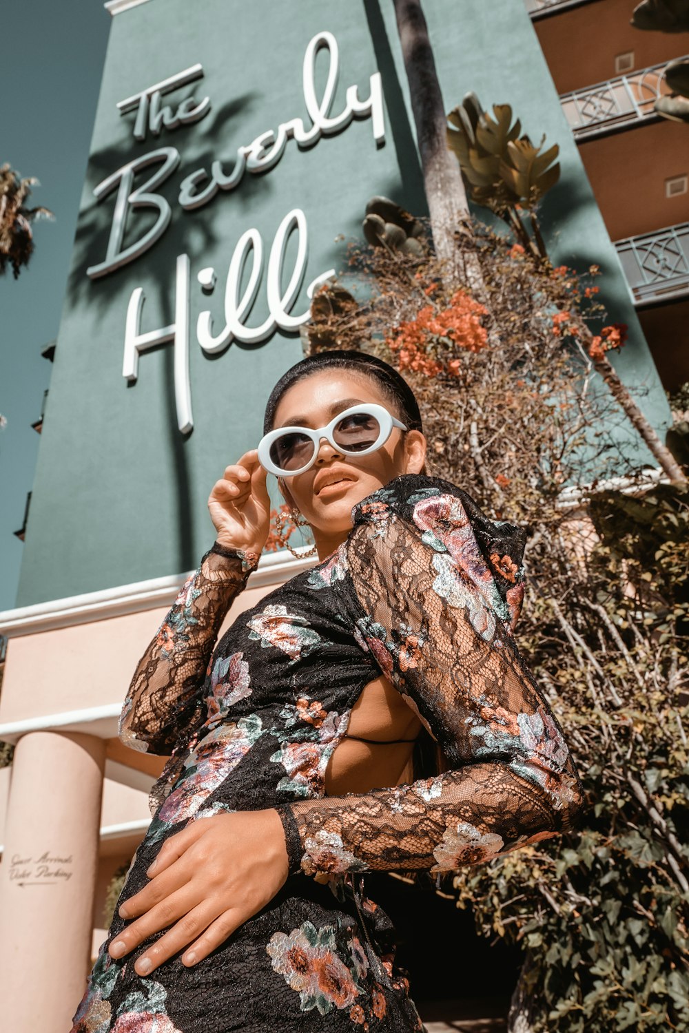 woman in brown and black floral long sleeve shirt wearing sunglasses sitting on white chair