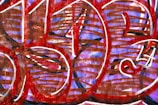 An abstract graffiti artwork featuring bold, rounded shapes filled with red and brown lines against a purple background. White outlines add contrast and definition to the overlapping forms.