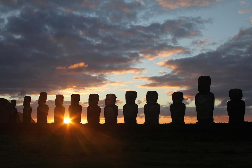 silhouette of people standing on rock formation during sunset