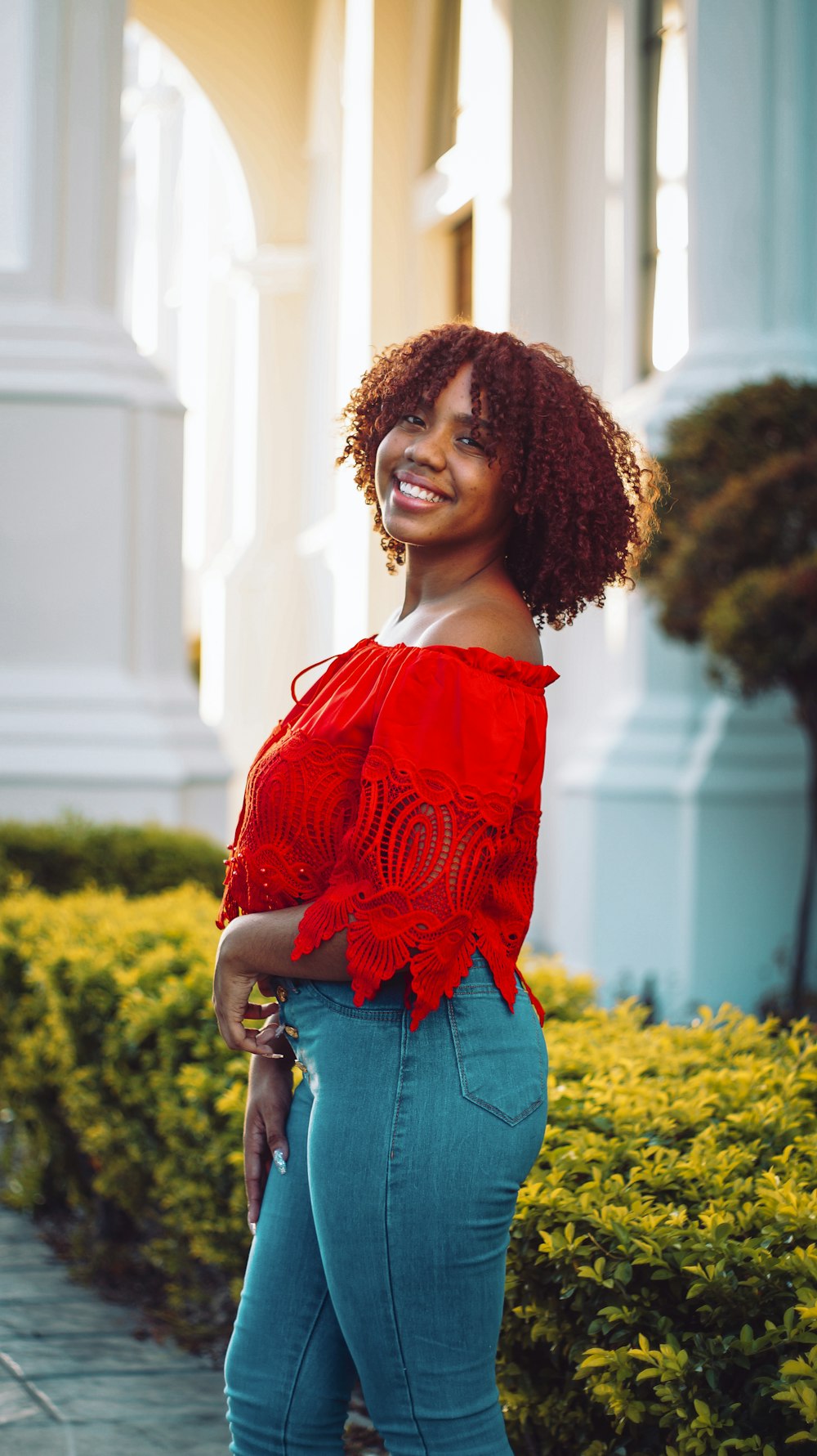 woman in red off shoulder shirt standing near yellow flower field during daytime