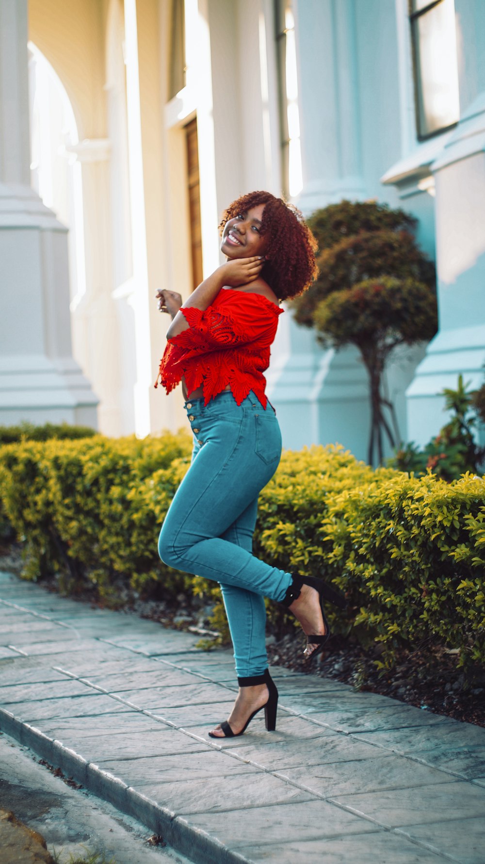 Woman in red shirt and blue denim jeans standing on pathway photo