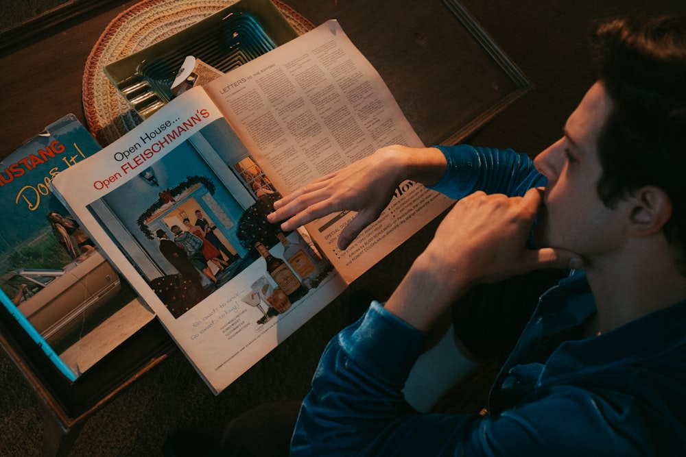 person in blue long sleeve shirt holding newspaper