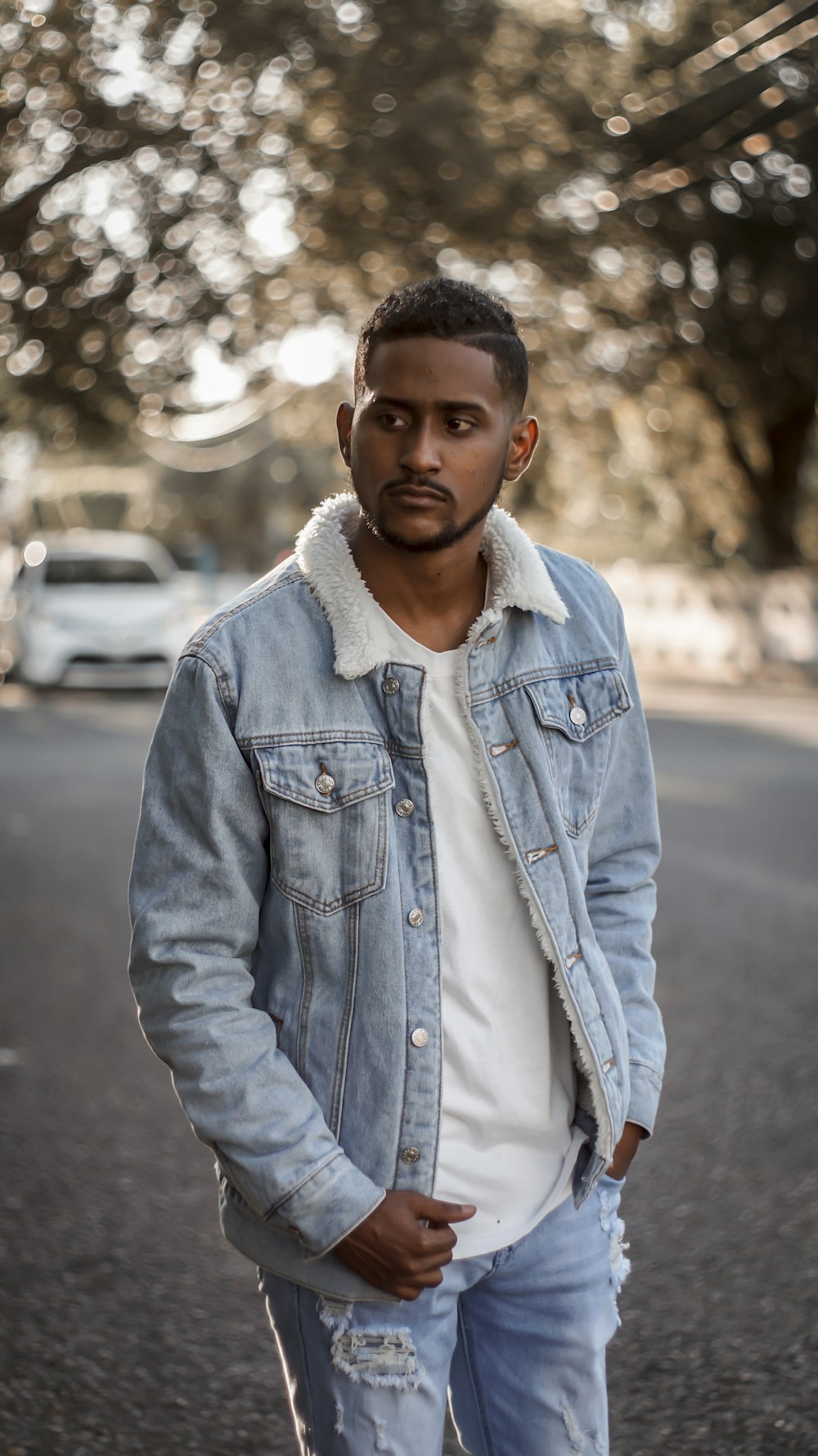 man in blue denim button up jacket standing on road during daytime