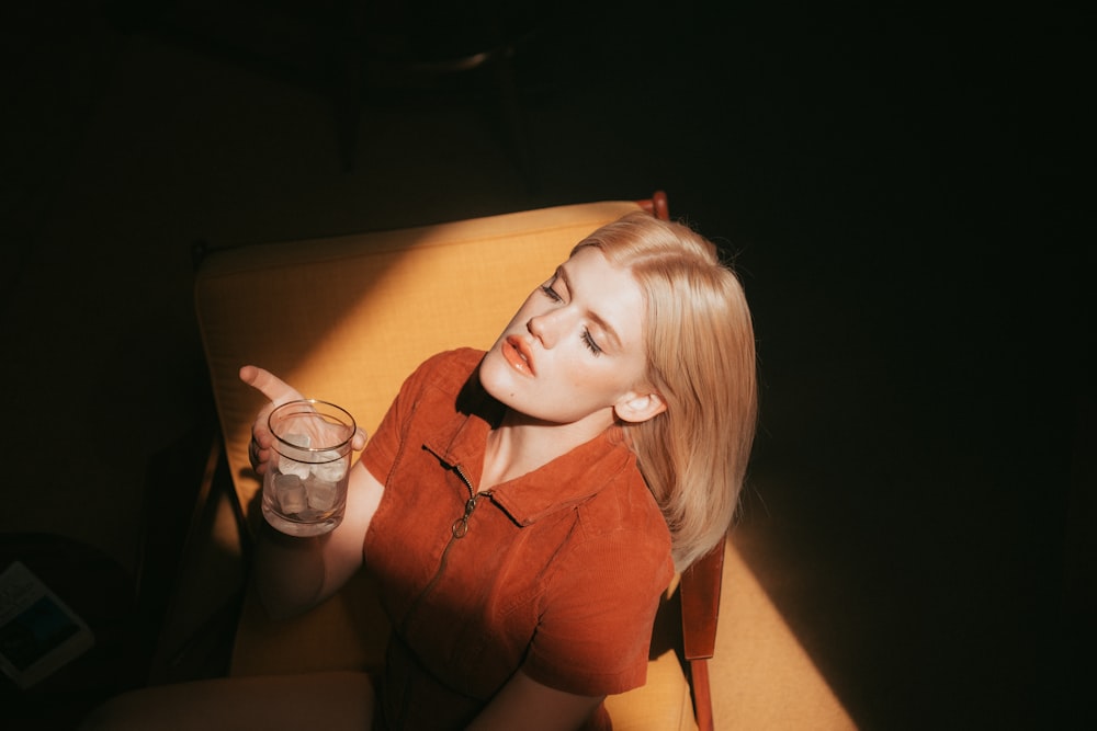 woman in orange sleeveless top holding clear drinking glass