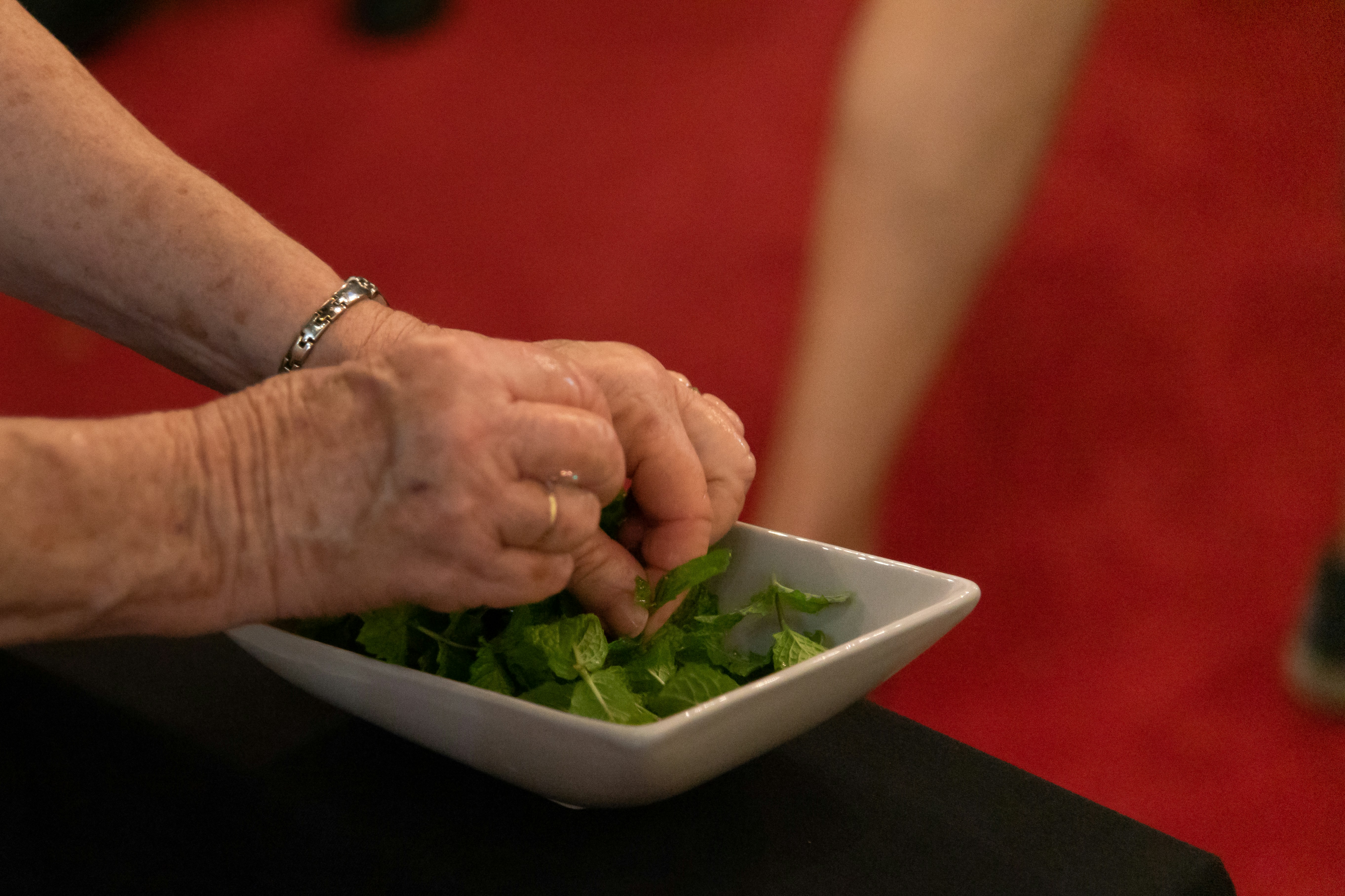 person holding green vegetable on white ceramic bowl