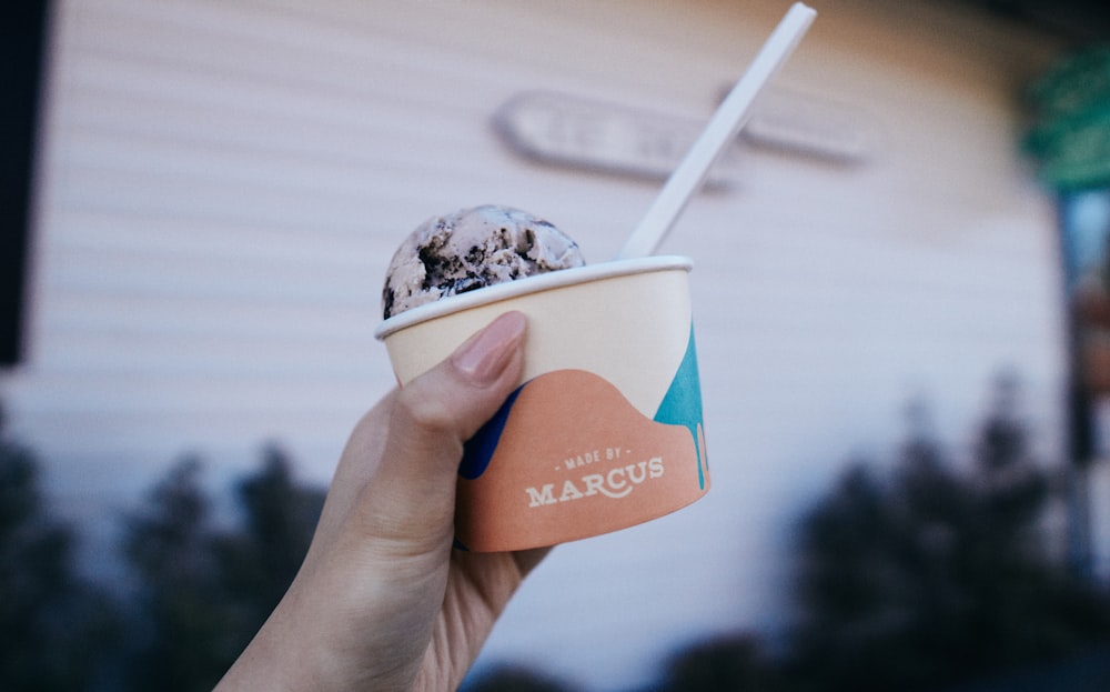 person holding blue and white ice cream cup