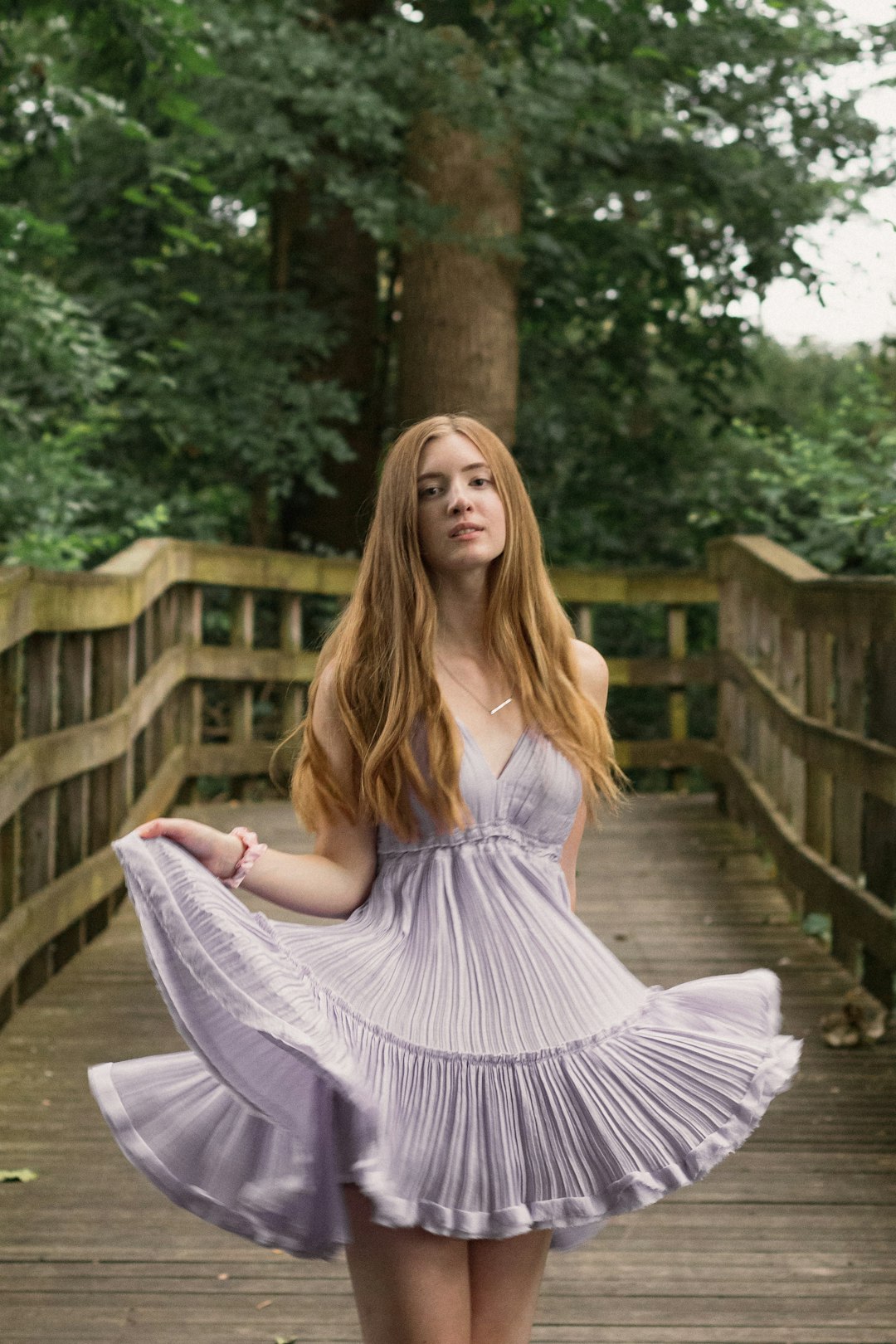 woman in white dress sitting on brown wooden bridge