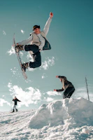 man in black jacket and blue denim jeans riding snowboard during daytime