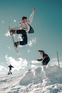 man in black jacket and blue denim jeans riding snowboard during daytime