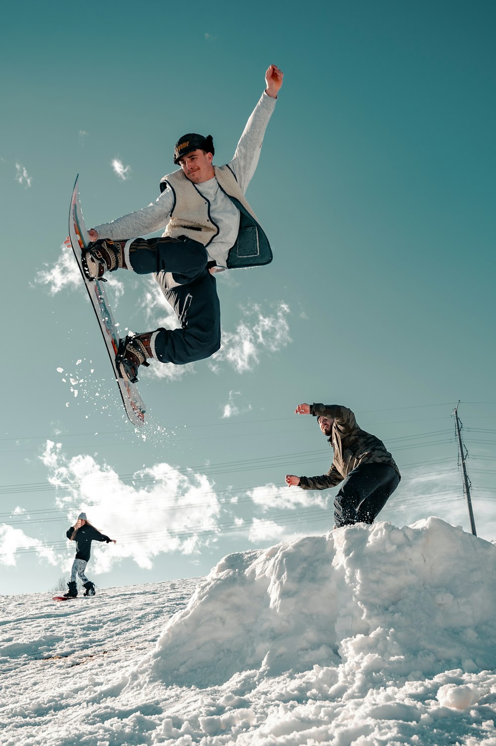 Uomo in giacca nera e jeans blu in denim che cavalca lo snowboard durante il giorno