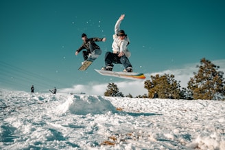 man in black and white jacket riding on snowboard during daytime