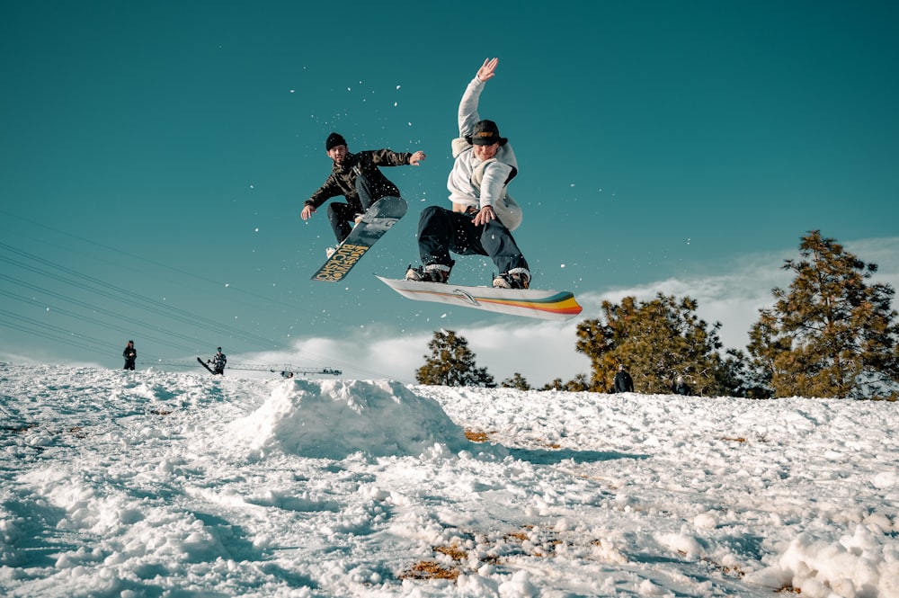 Uomo in giacca bianca e nera che cavalca sullo snowboard durante il giorno