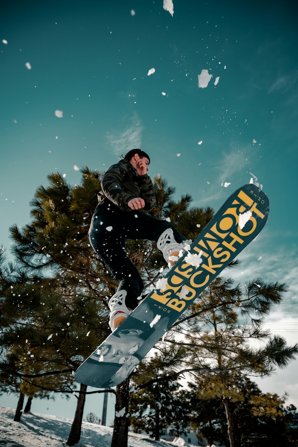 Mann in schwarzer Jacke fährt nachts blaues Snowboard