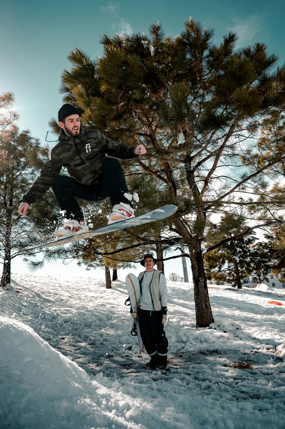 Hombre en chaqueta negra y pantalones blancos montando en snowboard negro durante el día