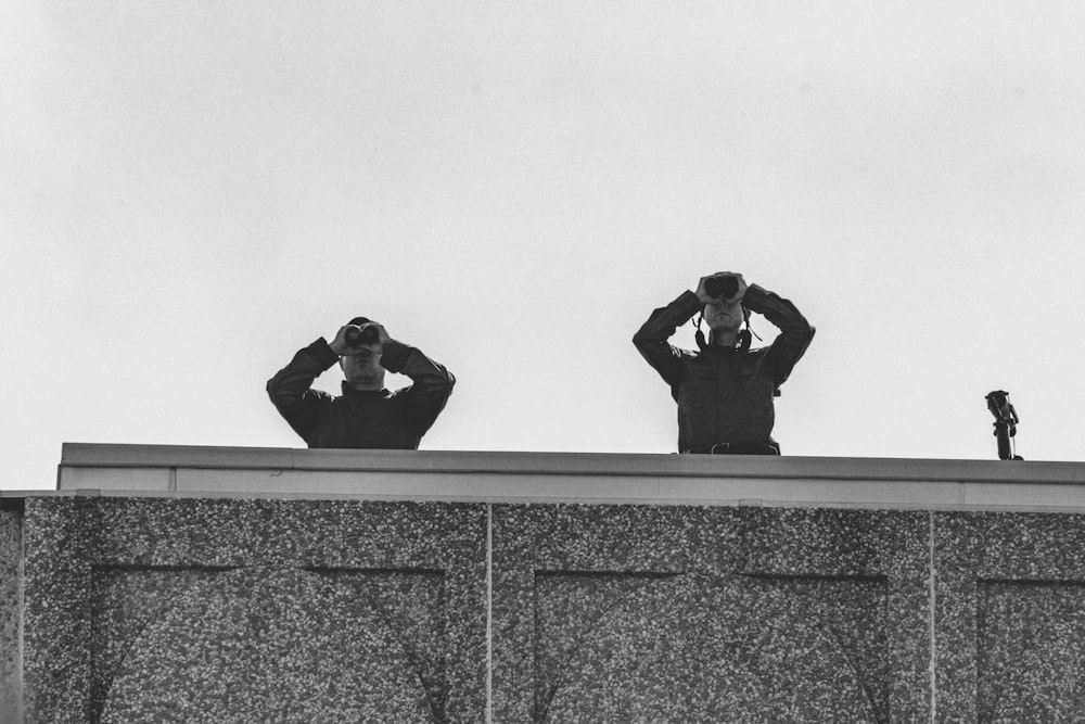 person in black jacket and black pants sitting on concrete wall