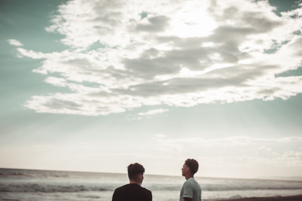 man and woman standing on beach during daytime