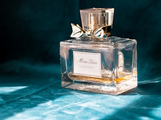 clear glass perfume bottle on blue textile