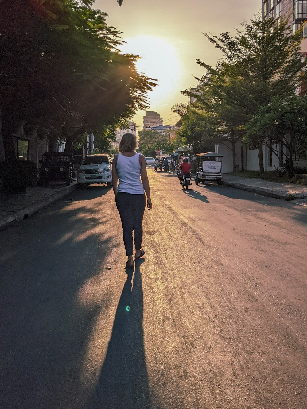 man in white t-shirt and black pants walking on street during daytime