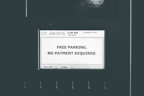 A screen displays a message indicating free parking with no payment required. The screen is labeled with 'ST. JOHN'S' at the top and shows a timestamp of '1:08 AM 4/9/2021' and 'Terminal: 1331-C'. There are buttons for 'Help/Info' and 'Langue' at the bottom of the screen.