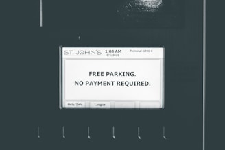 A screen displays a message indicating free parking with no payment required. The screen is labeled with 'ST. JOHN'S' at the top and shows a timestamp of '1:08 AM 4/9/2021' and 'Terminal: 1331-C'. There are buttons for 'Help/Info' and 'Langue' at the bottom of the screen.