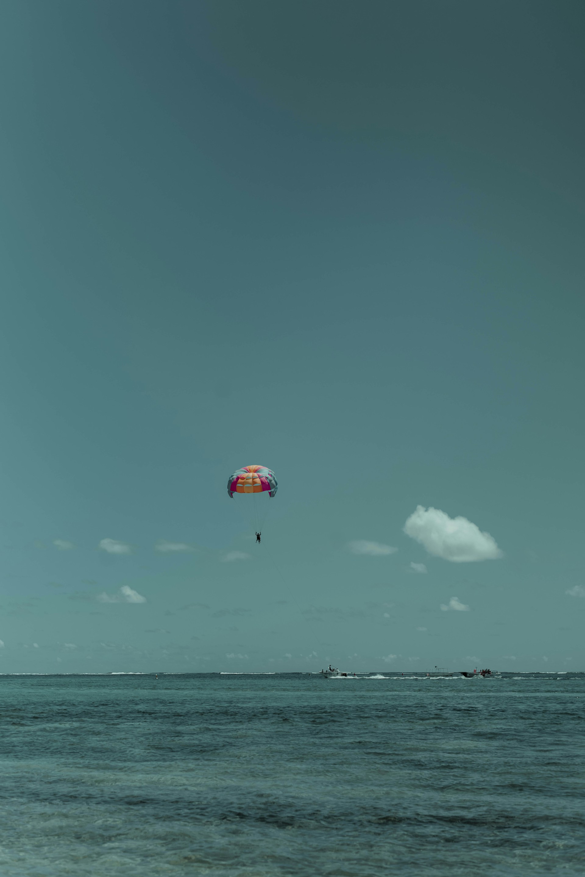 A thrilling parasailing experience over the ocean, showcasing a colorful parachute against a bright blue sky.