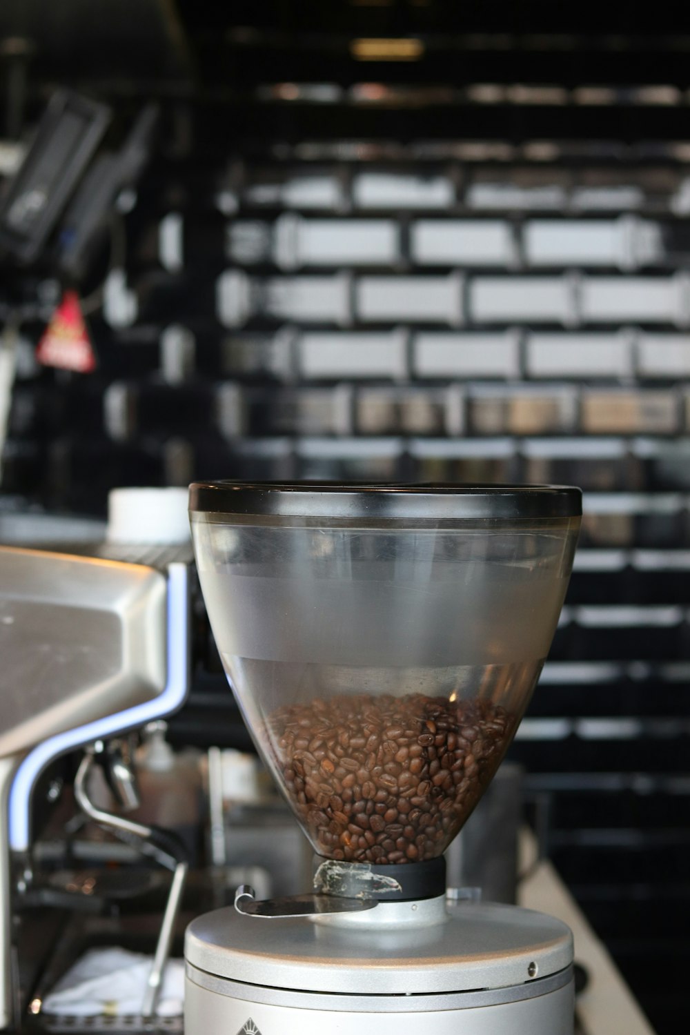clear glass cup on black coffee beans machine