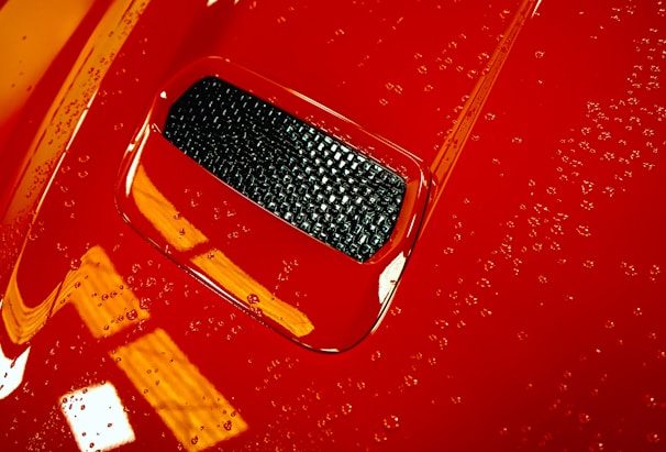 Exterior of a freshly washed red car with water droplets glistening on the paint