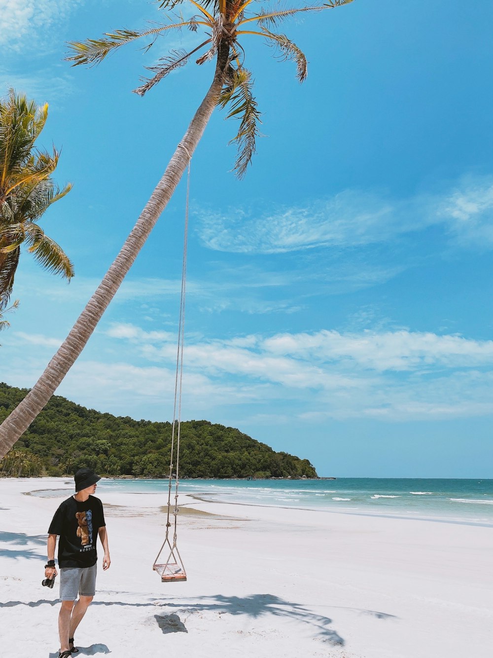 man in black shirt and blue denim jeans standing on beach during daytime