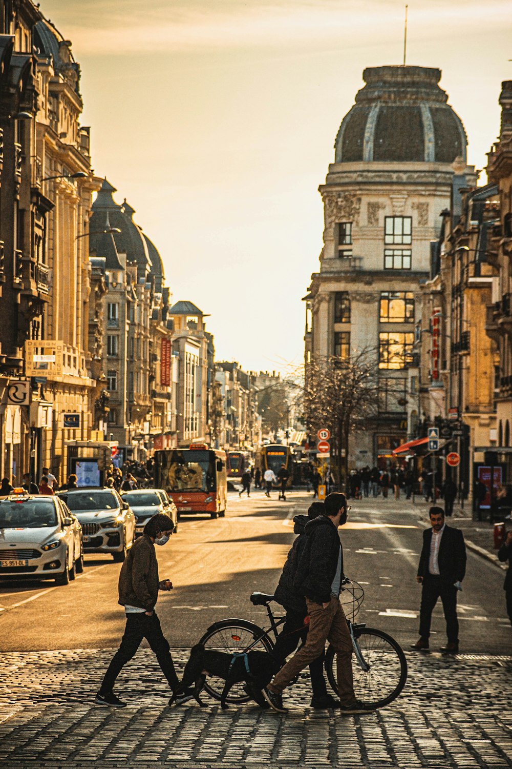 les personnes qui marchent sur le trottoir près des voitures et des bâtiments pendant la journée ;