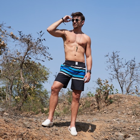 man in blue shorts standing on brown sand during daytime