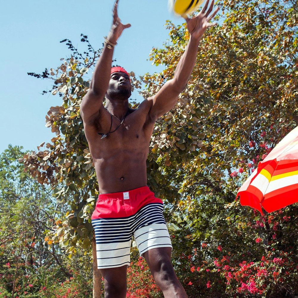 man in red white and black shorts holding yellow and red flag during daytime