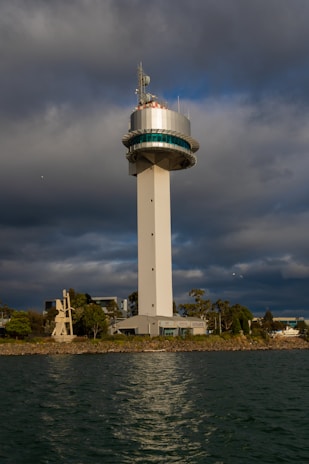 white and blue tower near body of water under gray clouds