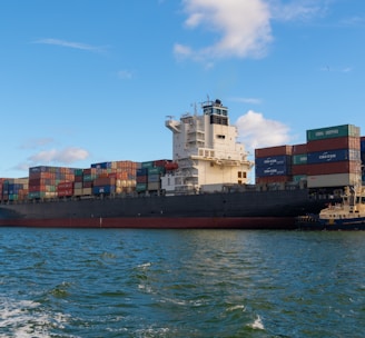 black cargo ship on sea under blue sky during daytime