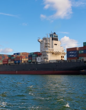 black cargo ship on sea under blue sky during daytime