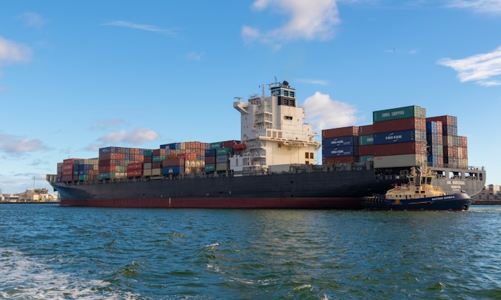 black cargo ship on sea under blue sky during daytime