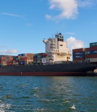 black cargo ship on sea under blue sky during daytime