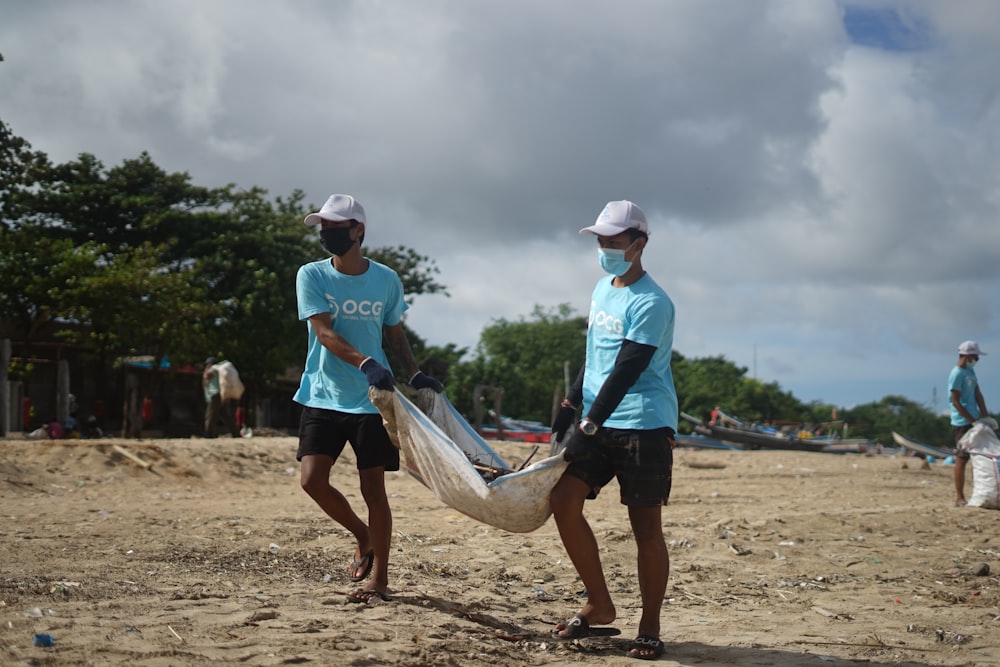 2 men in blue shirt holding white and blue canoe