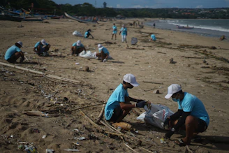 Children and families participating in a beach cleanup event, with waves gently rolling in the background.