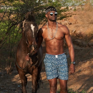 woman in blue and white floral skirt standing beside brown horse during daytime