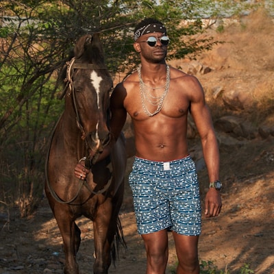 woman in blue and white floral skirt standing beside brown horse during daytime