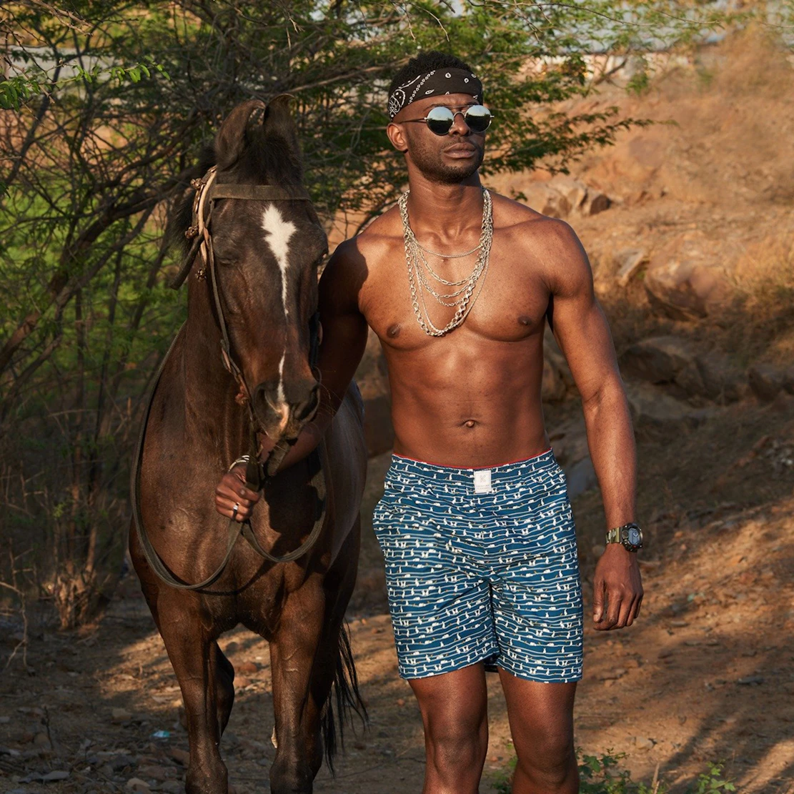 woman in blue and white floral skirt standing beside brown horse during daytime