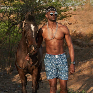 woman in blue and white floral skirt standing beside brown horse during daytime