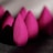 A close-up view of several pink makeup sponges arranged in a row. The focal point is on the texture of the sponges, showing their soft, porous surfaces. The sponges are teardrop-shaped, and the lighting creates shadows that emphasize their contours.